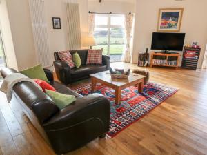 a living room with a leather couch and a coffee table at The Roundhouse in Auchterarder