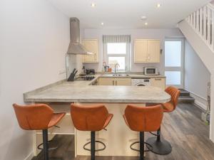 a kitchen with a large island with orange bar stools at Ty Bach, Great Orme in Llandudno