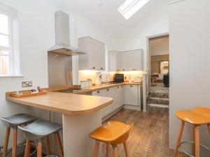 cocina con armarios blancos y encimera de madera en Lakeside Cottage en Macclesfield