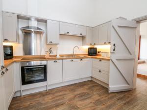 una cocina con armarios blancos y fregadero en Lakeside Village & The Potting Shed en Macclesfield