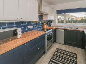 una cocina con armarios azules y blancos y fregadero en The Bungalow at Mill Falls, en Great Driffield
