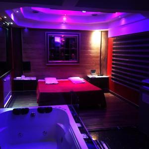 ブエノスアイレスにあるHotel Gildaのバスタブ付きの客室、紫色の照明付きのベッド1台