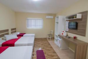 a hotel room with two beds and a desk at Pousada Vovó Dilma in Penha
