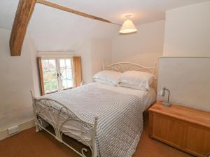 a white bed in a room with a window at Turnpike Cottage in Bideford