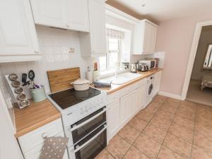 a kitchen with white cabinets and a stove top oven at Dove Farm Cottage in Louth