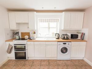 a kitchen with white cabinets and a sink and a microwave at Dove Farm Cottage in Louth