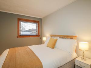 a bedroom with a bed with two lamps and a window at The Neuk in Elgin