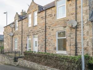 an old brick building with white windows on a street at The Neuk in Elgin