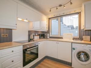 a kitchen with white cabinets and a washer and dryer at The Neuk in Elgin