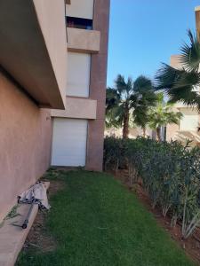 a side of a building with a yard with palm trees at Prestigia appartement opale in Marrakesh