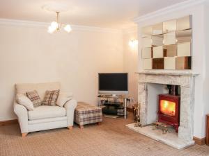 a living room with a fireplace and a chair and a television at Court Farm in Kidderminster