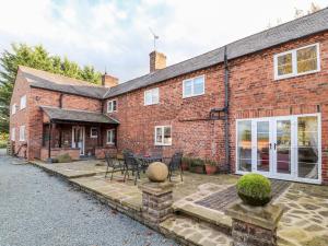 a brick house with a patio and tables and chairs at Milton Green Farm in Chester