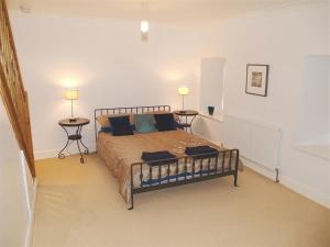 a bedroom with a bed with two tables and two lamps at Stable Cottage, Cardigan in Cardigan