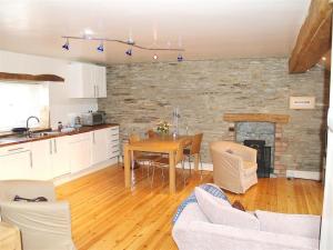 a kitchen and living room with a table and a fireplace at Stable Cottage, Cardigan in Cardigan