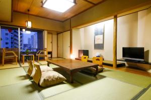 sala de estar con mesa, sillas y TV en Osaka Ryokan Kuramoto, en Osaka