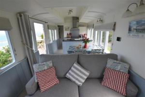 uma sala de estar com um sofá com almofadas em Clifftop Carriage em Aberporth
