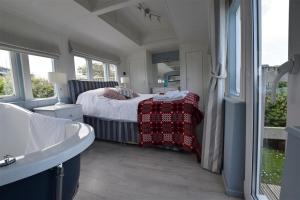 a bedroom with a bed and a tub and a sink at Clifftop Carriage in Aberporth