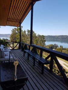 una terraza de madera con un banco y una guitarra en Turismo del Bosque, en Castro