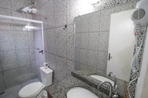 a white bathroom with a toilet and a sink at Pousada Vovó Dilma in Penha