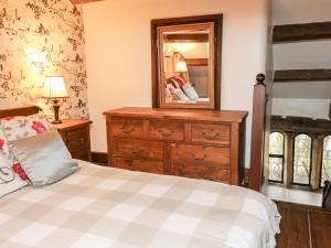 a bedroom with a bed and a dresser and a mirror at Monks Cottage in Skipton