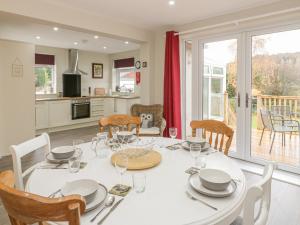 a dining room and kitchen with a white table and chairs at Awelon in Colwyn Bay