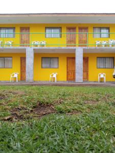 a yellow building with white chairs in front of it at Hotel San Juan in Coquimbo