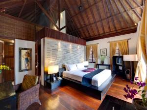 a bedroom with a large bed and a brick wall at Majapahit Beach Villas by Nakula in Ketewel