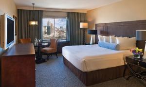 ラスベガスにあるエクスカリバーのベッド、デスク、テレビが備わるホテルルームです。