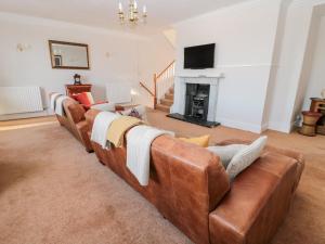 a living room with a brown leather couch and a fireplace at Tynemouth Village Penthouse in North Shields