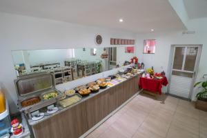 a kitchen with a long counter with food at Pousada Vovó Dilma in Penha +39 photos