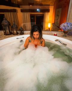 a woman is sitting in a bath tub filled with foam at Hotel Meissner Hof in Monte Verde