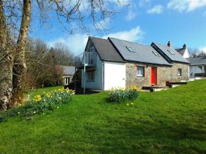 a house with a red door on a green lawn at Pond Cottage in New Quay