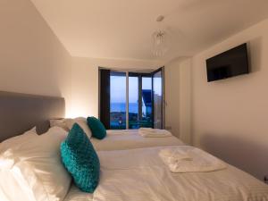 Un dormitorio con una cama con almohadas azules y una ventana. en Godrevy, en St Ives
