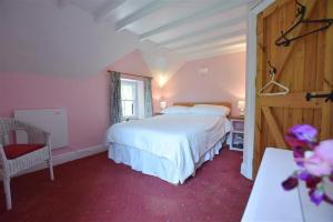a bedroom with a large white bed and a chair at Cwmbrandy Cottage in Fishguard