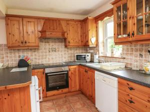 eine Küche mit Holzschränken und einem Waschbecken in der Unterkunft 18 Dalewood in Glengarriff
