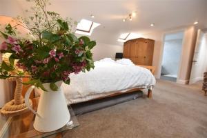 a bedroom with a bed and a vase with flowers on a table at Mill Barn Denant in Haverfordwest