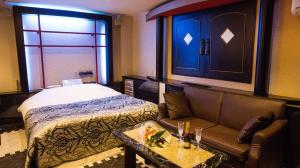 函館市にあるレステイ SakuRa（大人専用）のベッド、ソファ、テーブルが備わる客室です。