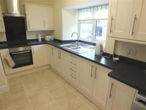 a kitchen with white cabinets and a sink and a window at Tremynydd Fawr in St. Davids +14 photos