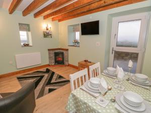 a dining room with a table and a fireplace at Ysgubor Ddegwm Bach in Beaumaris