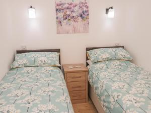 1 dormitorio con 2 camas, vestidor y una pintura en Ysgubor Ddegwm Bach, en Beaumaris