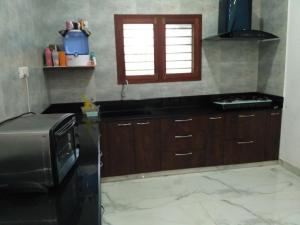 a kitchen with wooden cabinets and a microwave in it at Yaa Residency near VIT in Vellore