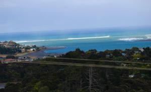 an aerial view of the ocean and a road at The Beach House on the Hill in Raglan
