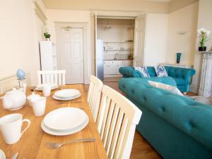 - un salon avec une table et un canapé bleu dans l'établissement Wessex View, à Weymouth
