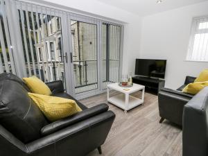 a living room with two leather couches and a tv at The Office Gardens, Apartment 1 in Whitby