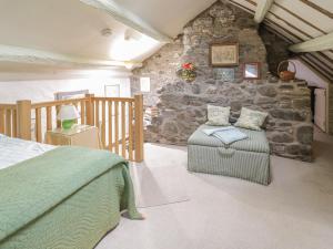 1 dormitorio con cama, silla y pared de piedra en Lower Dolgenau- The Cottage, en Caersws