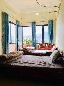 2 Betten in einem Zimmer mit großen Fenstern in der Unterkunft Peace House in Sa Pa