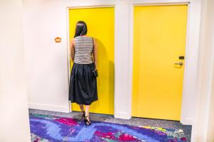 
a woman standing next to a wall with a blue wall at ibis Styles Brisbane Elizabeth Street in Brisbane
