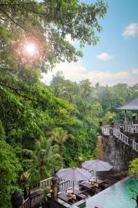 a resort with a pool and tables and umbrellas at Kawi Resort Ubud in Tegalalang