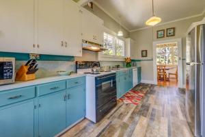 uma grande cozinha com armários azuis e electrodomésticos azuis em Ola'a House in Volcano Village em Volcano