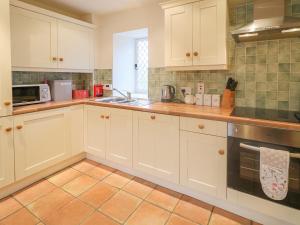 cocina con armarios blancos y suelo de baldosa en Robertson's Cottage, en Caledon